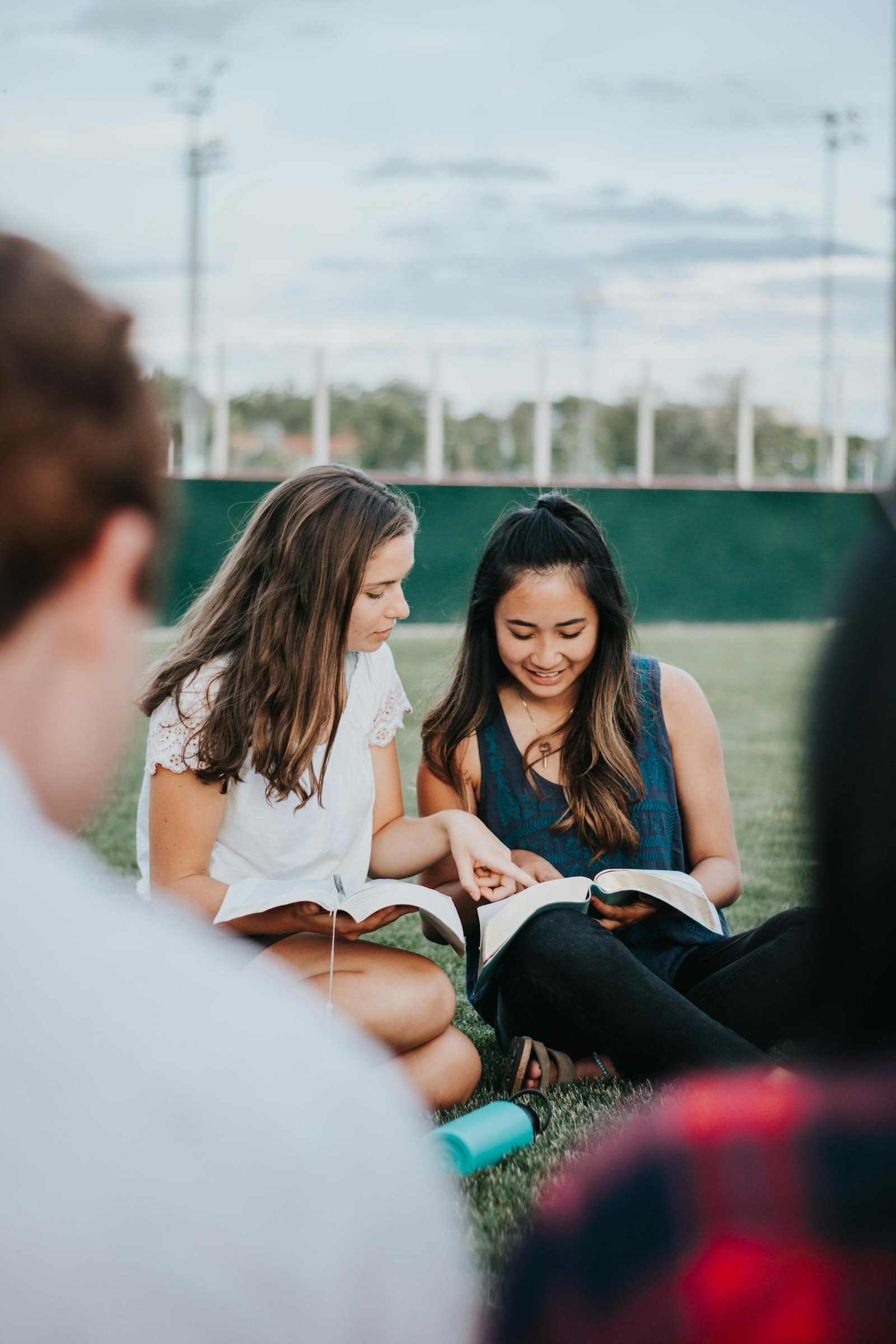 Two students reading their Bibles together outdoors.